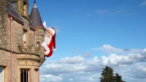 A giant Santa popping his head around the side of Belfast Castle with beautiful blue skies and clouds in the background