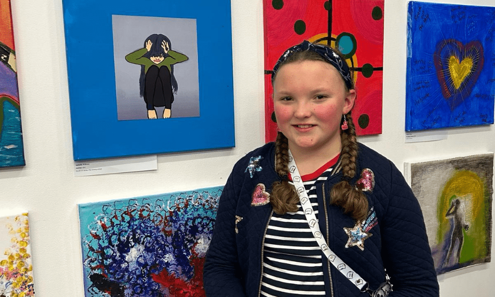 Isabella alongside her artwork at the Cancer Through Our Eyes exhibition